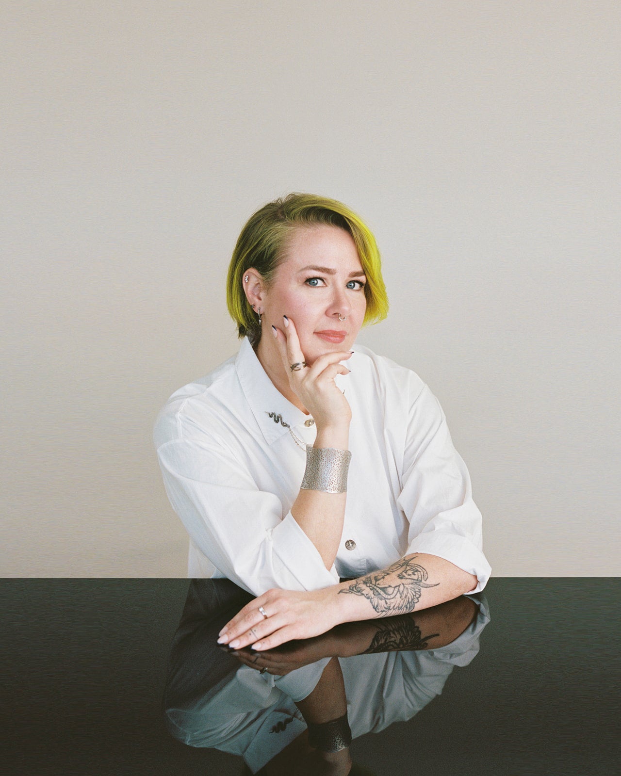 Portrait of Cult of Reason Skincare founder Angela Hugghins wearing white button down shirt and hand on her face