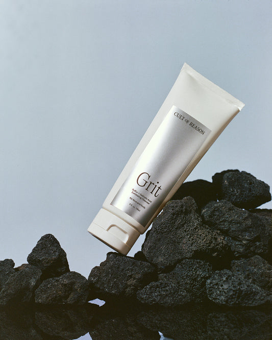 Image of Cult of Reason skincare product Grit, a sulfur-based facial cleanser with jojoba beads and pumice, pictured on black rocks
